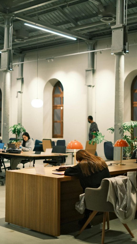 Espace de coworking lumineux avec plusieurs personnes travaillant à des bureaux partagés dans un bâtiment industriel rénové